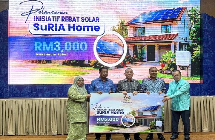 Group of five people on stage holding a large poster advertising the Suria Home solar rebate program.