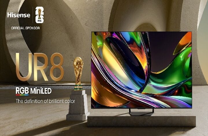 Hisense UR8 RGB MiniLED TV on a stand with sponsor logos and a World Cup trophy in the background.