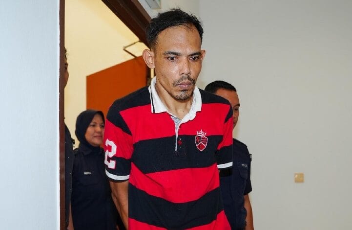 Man in a red and black striped polo being escorted by police officers through a doorway, with a woman and another officer in the background.