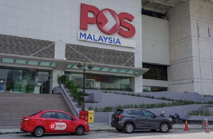 Exterior of a POS Malaysia building with a large red POS logo; a red taxi and a dark SUV parked in front, with a yellow public mailbox nearby.