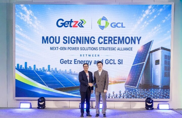 Two men in suits shake hands on a stage during an MOU signing ceremony, with a large backdrop showing Getz and GCL logos and text about a strategic alliance between Getz Energy and GCL SI.