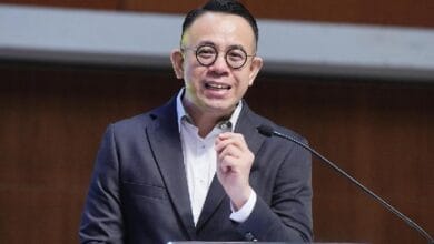 steven sim 2 - Wilayah.com.my Man in a dark suit and white shirt speaks at a podium with a microphone.