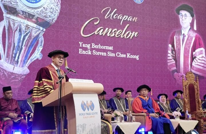 Male speaker in academic gown and cap delivers a speech at a podium during a graduation/convocation ceremony, with dignitaries seated nearby and a purple backdrop reading 'Ucapan Canselor' and 'Yang Berhormat Encik Steven Sim Chee Keong'.