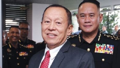 abdul halim aman - Wilayah.com.my Two men pose for a photo at a formal military event, with uniformed officers in the background, indoors.