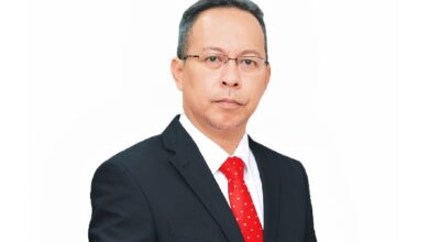 ahmad farrin cimb - Wilayah.com.my Professional headshot of a middle-aged man in a dark suit, white shirt, red tie, wearing glasses, on a white background.