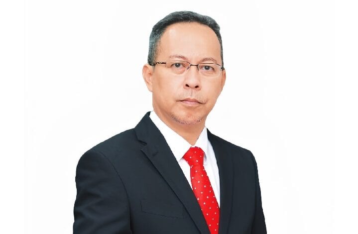 ahmad farrin cimb - Wilayah.com.my Professional headshot of a middle-aged man in a dark suit, white shirt, red tie, wearing glasses, on a white background.