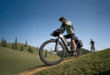 amflow bike - Wilayah.com.my Cyclist wearing helmet rides a fat-tire mountain bike up a grassy dirt trail on a sunny day.