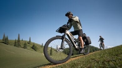 amflow bike - Wilayah.com.my Cyclist wearing helmet rides a fat-tire mountain bike up a grassy dirt trail on a sunny day.