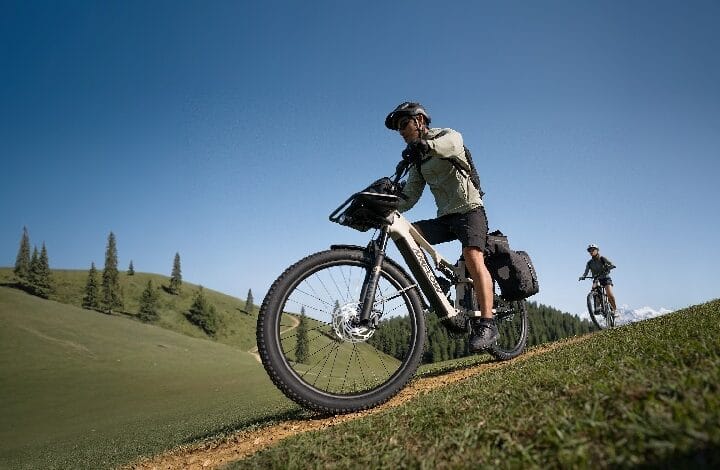 amflow bike - Wilayah.com.my Cyclist wearing helmet rides a fat-tire mountain bike up a grassy dirt trail on a sunny day.