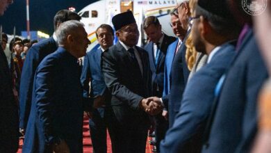 anwar 2 - Wilayah.com.my Officials in suits on a red carpet at night shake hands in front of a parked airplane, suggesting a formal arrival event.