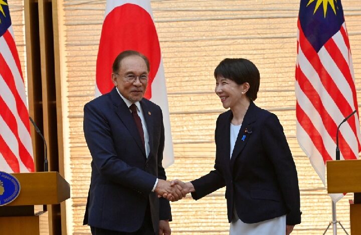 anwar japan 2 - Wilayah.com.my Diplomats from Japan and Malaysia shake hands during a formal event, with national flags in the background.