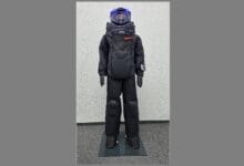 arclin bsst - Wilayah.com.my Humanoid robot in a black protective suit with a blue-lit head, standing on a mat.