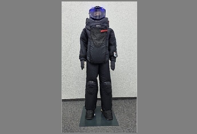 Humanoid robot in a black protective suit with a blue-lit head, standing on a mat.