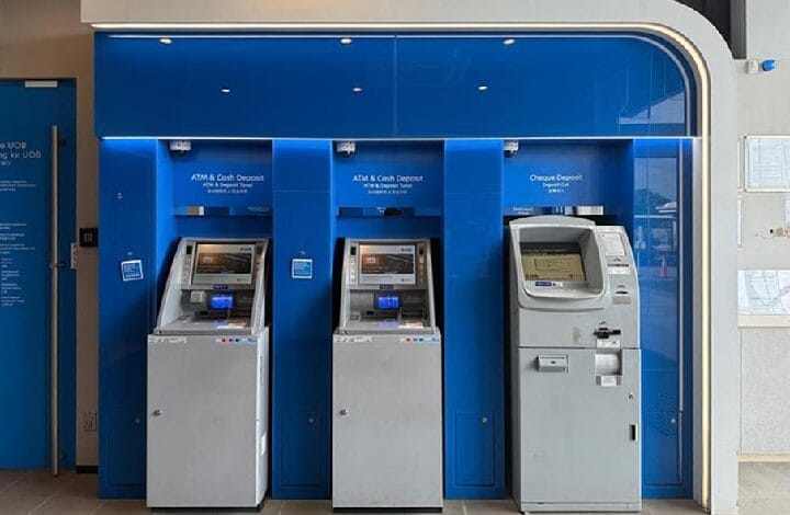 atm bank - Wilayah.com.my Three self-service ATMs in a blue bank alcove; two are for cash withdrawal/deposit and one is a cheque deposit machine nearby.