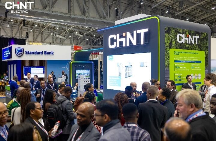 Crowded exhibition hall with a CHNT booth featuring large illuminated signage and a presentation screen in the foreground.