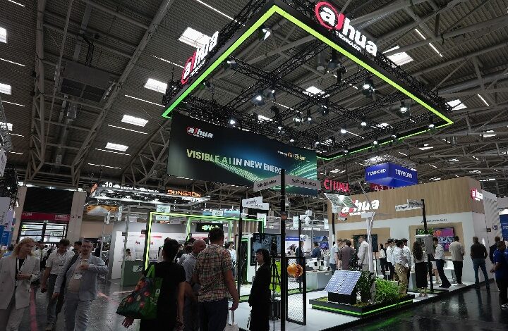 Dahua booth at a large exhibition hall with a neon-green, suspended canopy and crowd of attendees exploring security product displays on the floor below.