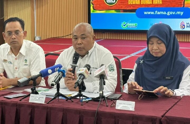 faisal iswardi 2 - Wilayah.com.my Three officials sit at a red table during a press conference; the man in the center speaks into a handheld microphone surrounded by reporters' microphones.