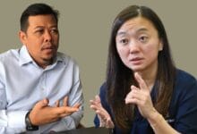 hannah 2 - Wilayah.com.my Two adults seated and talking; man on the left gestures with an open hand while the woman on the right speaks, using finger gestures to emphasize a point.