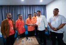 hasnul zulkarnain amanah - Wilayah.com.my Handshake between a man in a white shirt and a man in an orange shirt, with four colleagues watching in a small conference room.