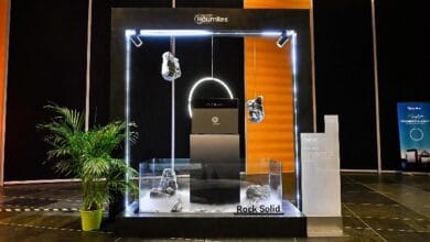 Glass display with a neon-lit frame showing suspended and base rock samples, labeled 'Rock Solid' in a showroom setting