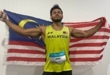 irfan - Wilayah.com.my Male Malaysian sprinter in a yellow MALAYSIA singlet, arms outstretched holding the Malaysian flag behind him; SEA Games bib reads IRFAN.