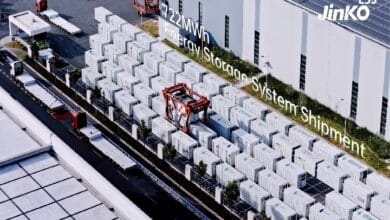 jinko ess - Wilayah.com.my Outdoor yard of energy storage containers beside a warehouse; red forklift visible, overlay text reads '22MW Energy Storage System Shipment', ESS Jinko logo in corner.