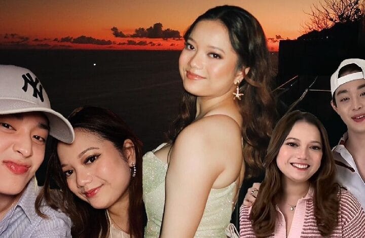 Group of five young friends posing for a sunset beach selfie; the central woman wears a pale-green dress and smiles as others surround her.