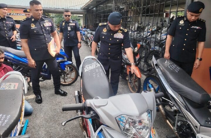 mod motor - Wilayah.com.my Group of uniformed police officers inspecting parked motorcycles in a fenced area; one officer leans over a bike while others observe.