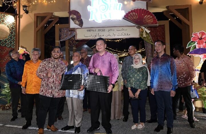 Group of people posing with gift bags at a festive night event under string lights.