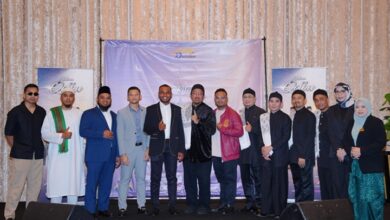 nasyid - Wilayah.com.my Group of men and women in formal attire posing on a stage with a purple backdrop at an event.
