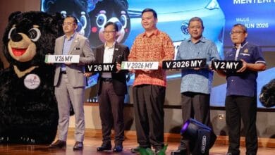 no plate 2 - Wilayah.com.my Six men on a stage holding novelty license plates, with a bear mascot on the left and a blue car backdrop.
