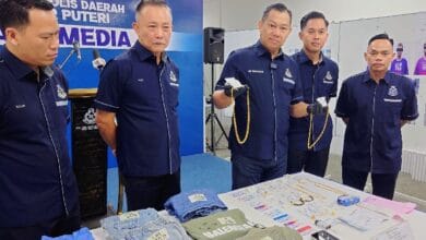 pdrm johot - Wilayah.com.my Five uniformed police officers stand behind a table of seized clothes and jewelry at a media briefing.