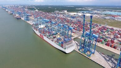 pelabuhan klang - Wilayah.com.my A container ship docked at a busy port with blue gantry cranes loading colorful containers onto the cargo ship.