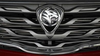 proton - Wilayah.com.my Front grille of a red car with a chrome shield-shaped emblem centered on the grille.