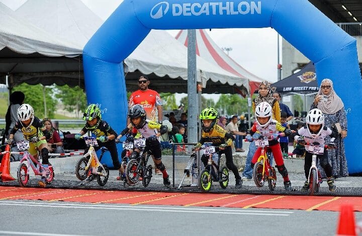 pushbike lion rocket - Wilayah.com.my Young children on small bikes race at a start line under a blue Decathlon arch, with spectators watching nearby.