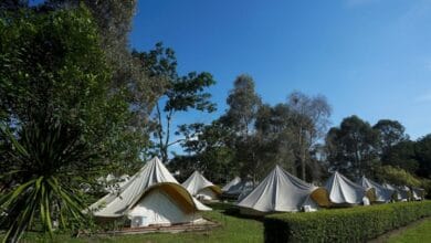putrajaya - Wilayah.com.my Row of beige canvas tents pitched in a grassy campground under a clear blue sky