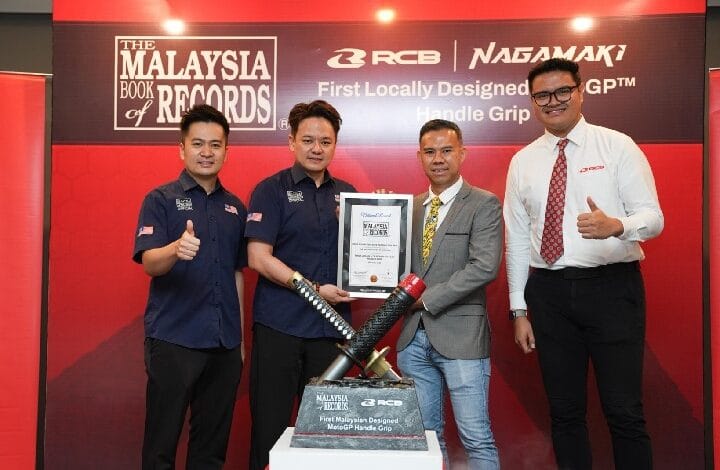 rcb 2 - Wilayah.com.my Four men pose on a red stage, holding a certificate and a large handle grip trophy for a locally designed MotoGP handle grip.