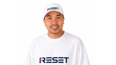 reset - Wilayah.com.my Man wearing a white cap and T-shirt with the blue 'RESET' logo, smiling.