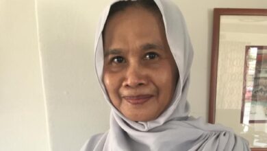 roslizawati ali - Wilayah.com.my Smiling woman wearing a light gray hijab indoors, facing the camera.