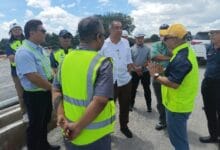 salleh said keruak - Wilayah.com.my Group of workers and managers in high-visibility vests listening to a man in a white shirt on a construction site.