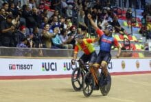 shah firdaus - Wilayah.com.my Two cyclists celebrate a victory on a wooden velodrome as the crowd cheers in the stands behind them.