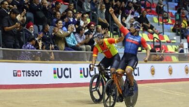 shah firdaus - Wilayah.com.my Two cyclists celebrate a victory on a wooden velodrome as the crowd cheers in the stands behind them.