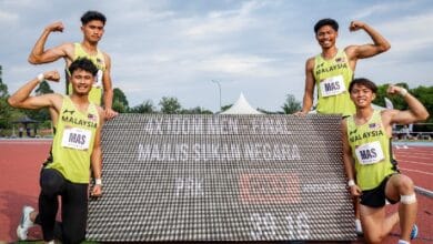 sport 2 - Wilayah.com.my Four Malaysian sprinters on a track pose with a large banner, flexing their arms and smiling.