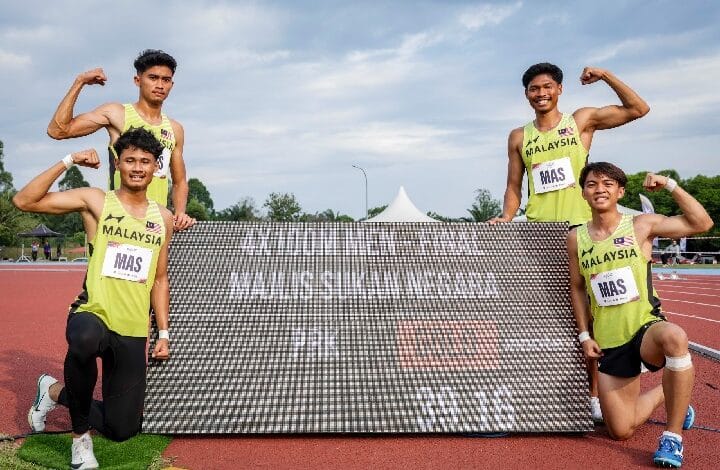 sport 2 - Wilayah.com.my Four Malaysian sprinters on a track pose with a large banner, flexing their arms and smiling.