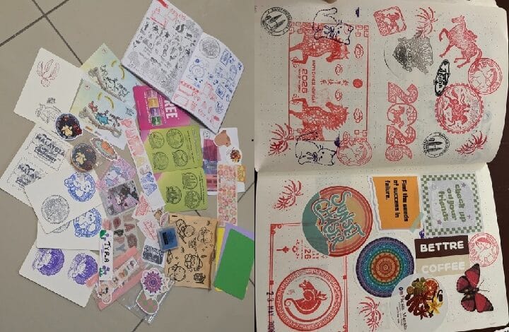 stamp 2 - Wilayah.com.my A collection of decorative stamps, stickers, and cutouts spread across a tiled floor. On the right, an open notebook shows stamp designs and colorful sticker sheets on the pages.