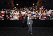 the furious 2 - Wilayah.com.my Two men stand center-stage posing for a photo as a large, excited crowd fills the dark theater behind them, holding up posters and making peace signs.