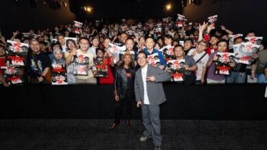 the furious 2 - Wilayah.com.my Two men stand center-stage posing for a photo as a large, excited crowd fills the dark theater behind them, holding up posters and making peace signs.