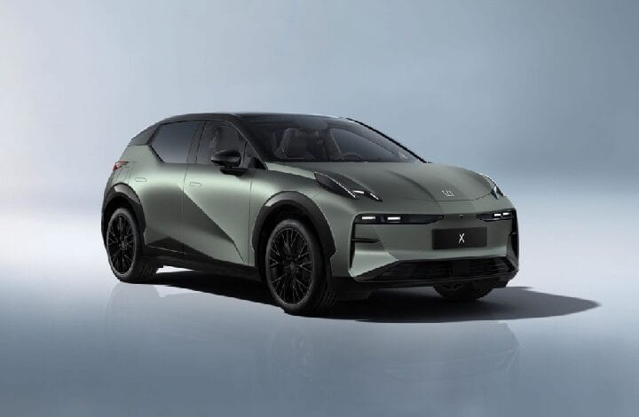 Three-quarter front view of a gray-green electric SUV with a black roof and dark wheels.