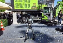 zoomlion komatek 2 - Wilayah.com.my Humanoid robot performing in a plaza during a construction equipment launch, with a bright green excavator and onlookers in the background.