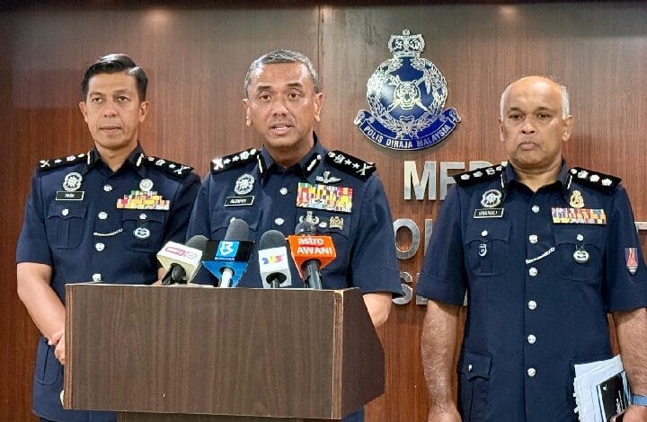 alzafny - Wilayah.com.my Three senior police officers in dark blue uniforms stand at a podium with microphones during a press briefing, Malaysia police emblem visible on the backdrop.
